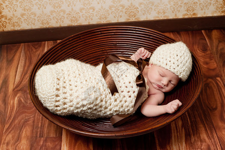 天大的新生女婴睡在一个钩编的奶油色茧里图片