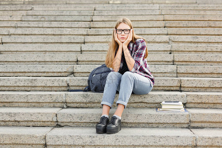 在大学校园的户外楼梯上坐着心烦的学生女孩图片