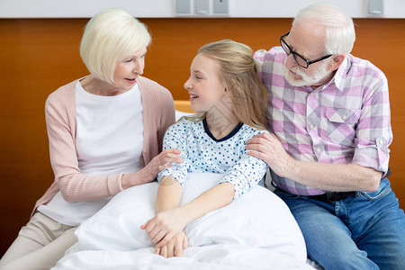 祖父母和笑着微笑的孙女坐在医院图片