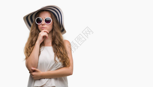 身戴太阳镜和夏帽的金发年轻女金发美女面对严肃的面孔思考问题图片