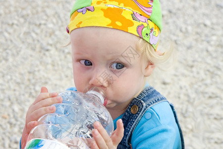 可爱的金发小孩从一个大塑料瓶里啜饮着水图片