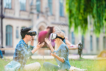 虚拟现实头戴着电脑坐在公园绿草地上的虚拟真人耳机中多文化学图片