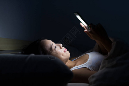 妇女使用手机晚上躺图片