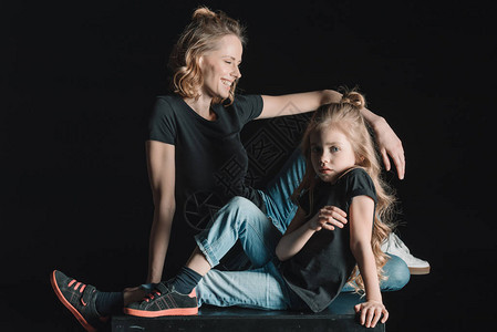 时髦的笑着的母亲和女儿坐在立方体上图片