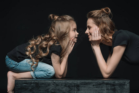 时尚的女儿和母亲笑着看对方的一面彼此孤立图片