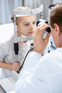眼科医生对诊所使用切开灯光检查儿童视力的作物图片
