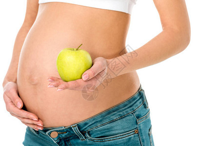 孕妇触摸肚子和持有孤立在白色上的绿苹果的切腹和怀着青苹图片