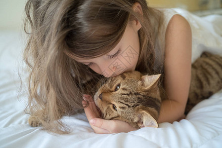 白种女孩在床上抱着猫图片