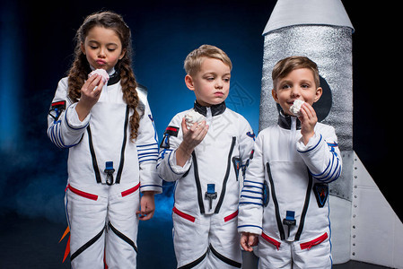 三个穿着宇航员服装的可爱小孩在火背景图片