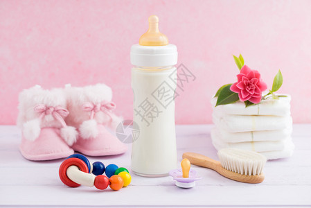 婴儿瓶奶嘴机理发刷尿布靴子和粉背景图片