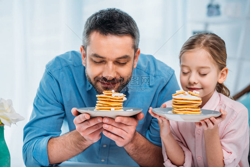 父亲和小女儿的肖像在家里吃早图片
