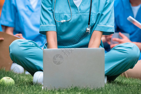 医科学生用笔记本电脑在绿草上学背景图片