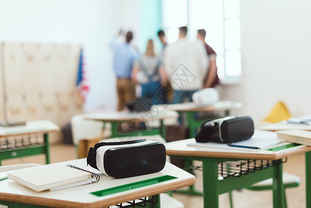 教师和高中学生在教室里排在后面的桌子上的虚拟现实头版耳机图片