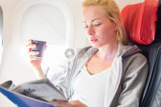 机舱内喝咖啡读杂志的女性图片