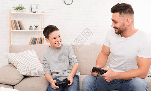 快乐的父亲和儿子在家里玩电子游戏图片