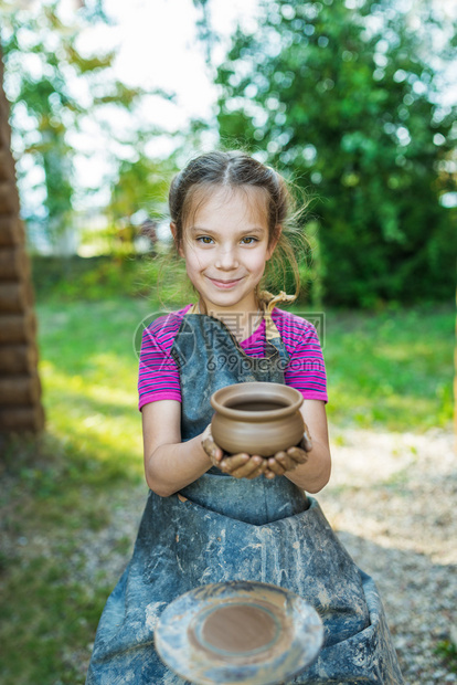 在陶工轮锅上生产的微笑小女孩图片