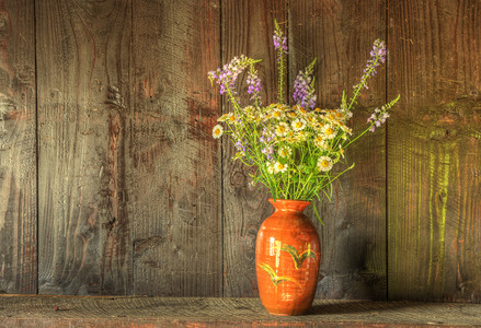 风化木质背景下乡村花瓶中干花的静物画图片