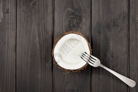 成熟的椰子一半和金属叉子椰奶的顶视图图片