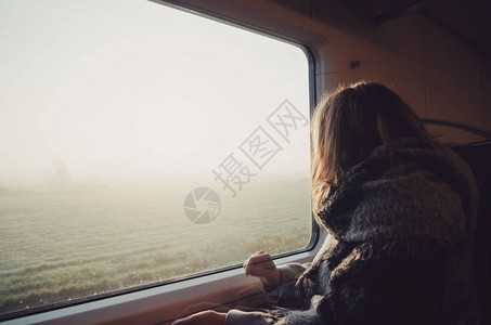 火车上的女孩透过窗户看背景图片
