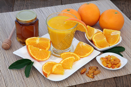 用新鲜的榨橙果汁维他命药片和在橡树本底竹子上的蜂蜜图片