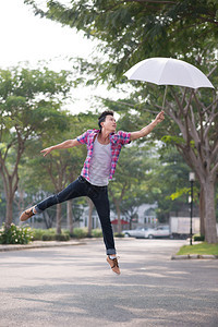 亚洲人手握着雨伞跳过图片