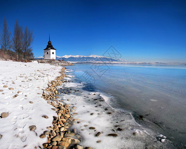 LiptovskaMara湖的冰冻水域非常罕见这座塔曾经是圣母玛利亚历史教堂和罗哈斯山脉的一部分图片