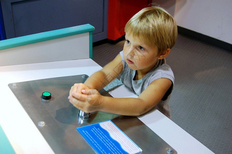 年轻人在沃森岛的迈阿密儿童博物馆操作一个模型展览的控制装置图片