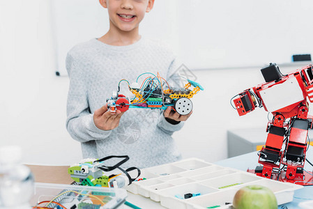在STEM课程中展示手工制造机器人模型的男学生图片
