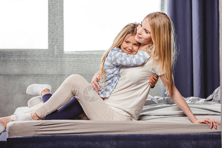 快乐的母亲和女儿穿着睡衣坐在背景图片