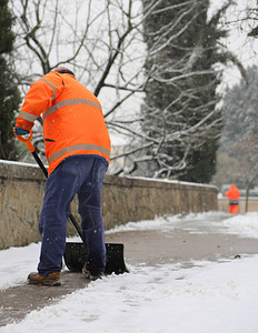 工人在从人行道铲雪时穿着图片