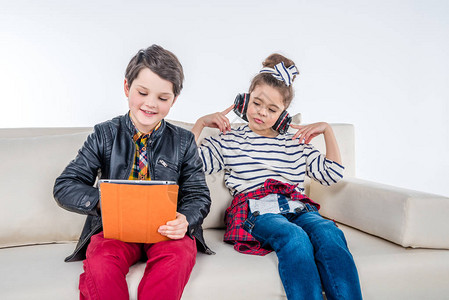儿童耳机和数字平板电脑坐在沙发上孤立在图片