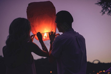 年轻夫妇晚上在河滩上放天灯的背影图片