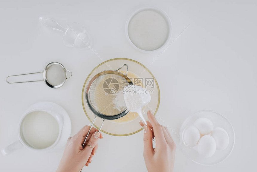 人在做用灰色隔开的煎饼时筛面粉的顶部视图图片