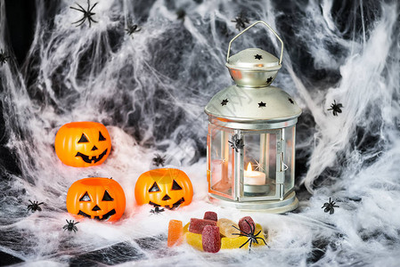 带糖果和点灯的万圣南瓜在蜘蛛网背图片