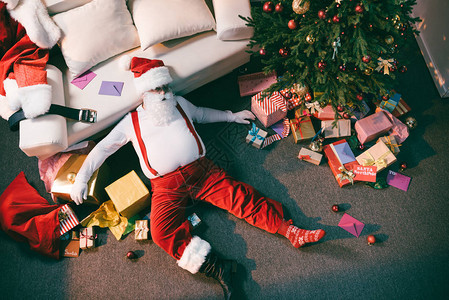 从头顶看到疲惫的圣诞老人躺在房间的地板上图片