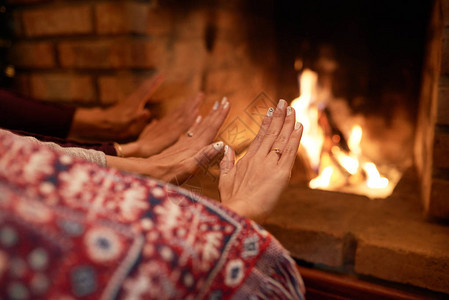 夫妇在家里的壁炉旁暖手背景图片
