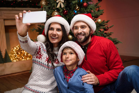 圣诞晚夜戴着圣塔帽的年轻快乐家庭用图片