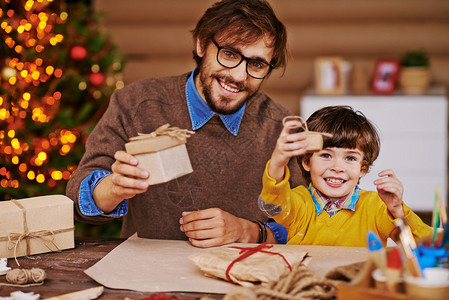 年轻男人和小男孩拿着圣诞礼物的礼品盒图片