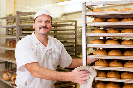 面包师早上站在面包店里做面包图片