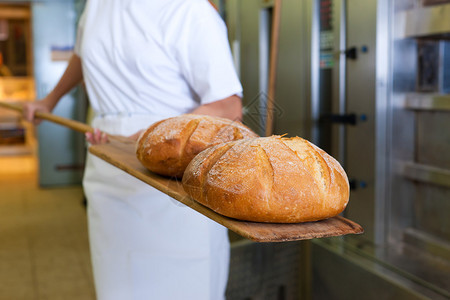 面包师在面包店烤新鲜面包图片