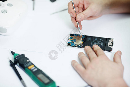 用各种工具在维修店上拆卸现代手机设备电路板图片