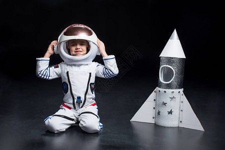 穿着太空服跪在火箭附近并调整头盔的微笑的图片