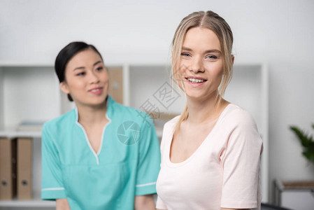 年轻护士微笑看着有魅力的金发病人背景图片