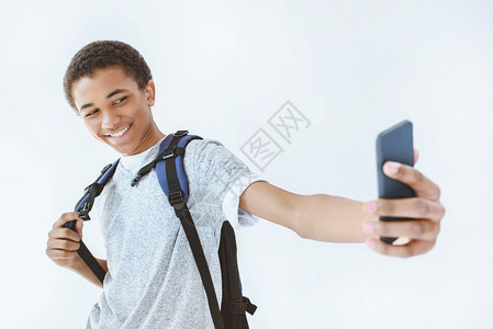 笑的非裔美国少年男孩在白色孤立的智能手机上图片