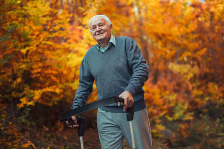 快乐的老年残疾人在秋季公园助推行车中享受散步生活图片