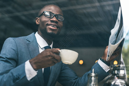 带着咖啡杯在咖啡馆阅读报纸的美籍非洲商人AfricanAfricanbusi图片