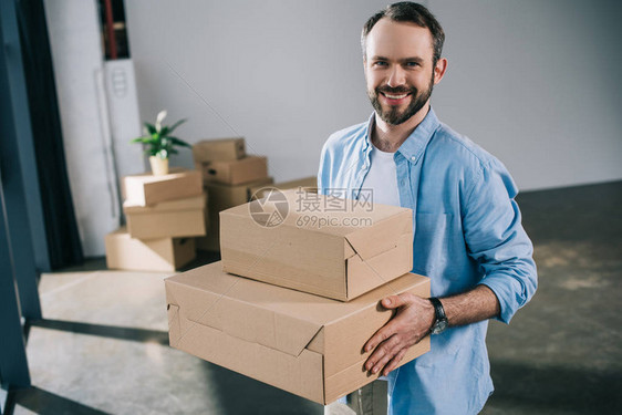 在异地安置期间快乐的胡须男子拿着箱子和图片