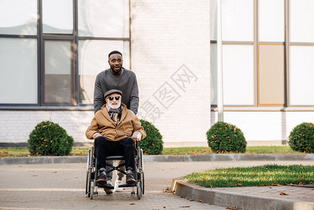 坐在轮椅上幸福快乐的老年残疾人和非洲裔美国人一图片