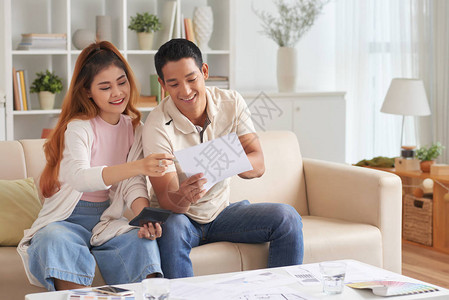 年轻亚洲夫妇在新房子里规划家庭预算微笑和交谈的肖像图片