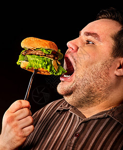 胖子吃快餐仓鼠不耐烦超重者通过在叉口吃汉堡来破坏健康食品垃圾饭导致黑暗图片